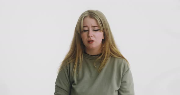 Sad Doubting Woman with Shifty Eyes Poses at White Wall