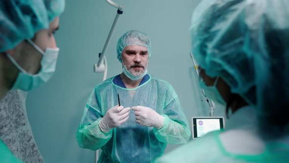 Surgeon Having a Talk with People Wearing Protective Masks and Gowns