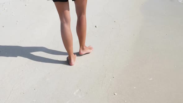 Ultra slow motion shot of legs and feet of young caucasian woman walking on sand in Thailand