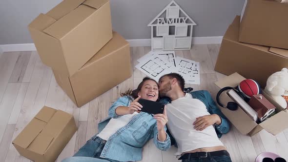 Young Happy Couple Posing on Smartphone Camera with Boxes on the Background