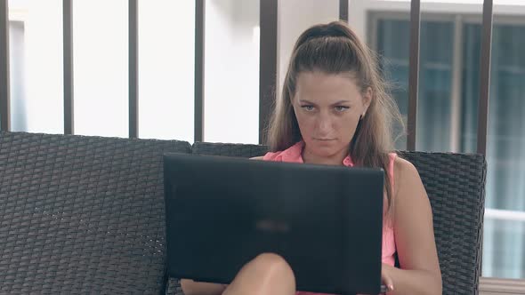 Tanned Woman in Earings Sits on Lounger Types on Laptop