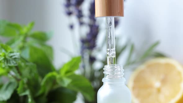 Essential oil drips from a pipette into a glass bottle. Eco cosmetics, body and hair care