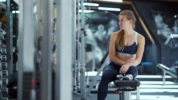 Woman relaxing after working out with dumbbells in gym