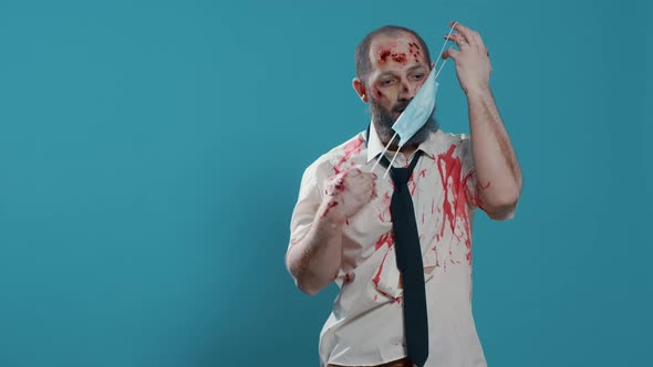 Braindead Office Zombie with Covid Protection Mask and Bloody Scars Standing on Blue Background