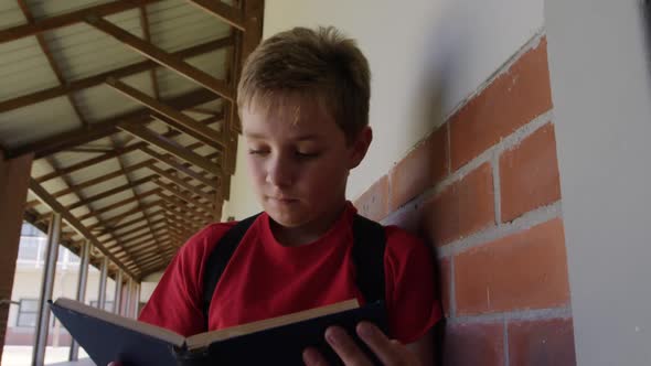 Boy reading books in the school corridor