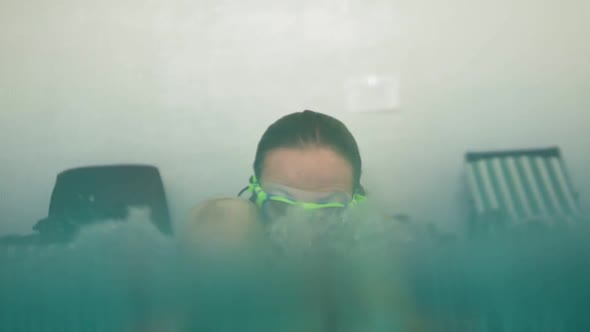 Cute Blonde Toddler is Diving Under the Water Together with His Mother in Special Protective Glasses