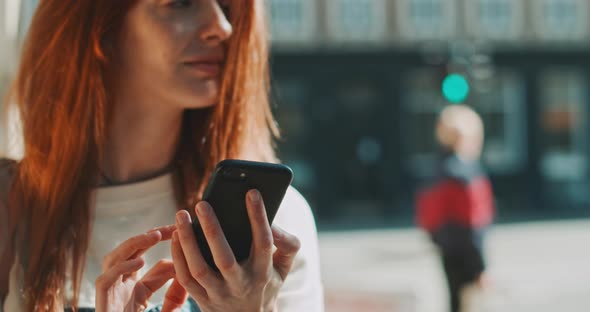 Young beautiful redhead laughing while using a mobile