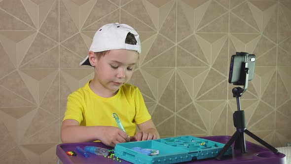 Child in a Baseball Cap Records a Video for the Internet. A Small Blogger Is Talking on Video