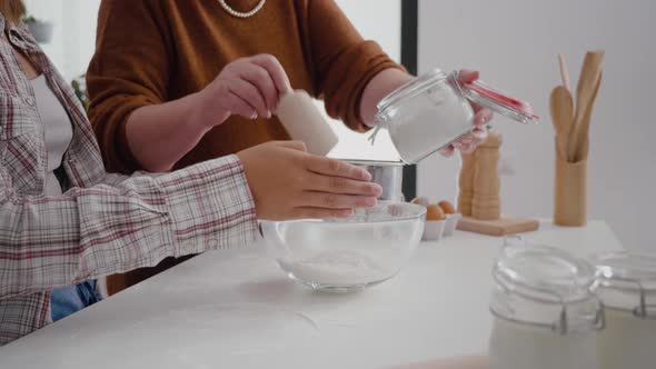 Closeup of Grandmother Hands Putting Flour in Strainer While Granddaughter Sift Ingredient