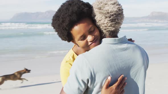 Happy african american couple dancing and embracing on sunny beach