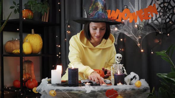 Excited girl lighting candles sitting in dark room, celebrating Halloween night.