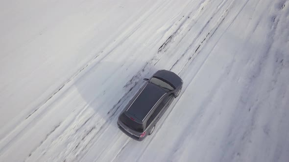  Family car driving on a dirt road in snow covered winter field.