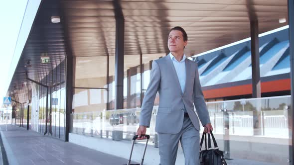 Elegant businessman walking with suitcase along the airport. Young mail entrepreneur.