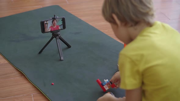 A Little Boy Plays and Talks with His Friends and Relatives Through a Video-call Using a Smartphone