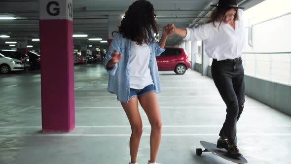 Happy Women Having Fun And Skateboarding At Parking