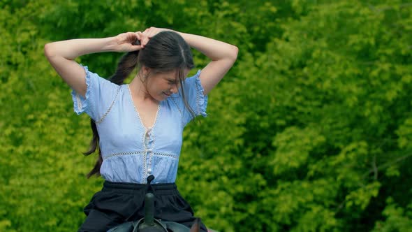 Young Smiling Woman in Blue Shirt Riding a Horse - Lets Her Hair Down