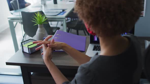 Mid section of african american woman using hands sanitizer at modern office