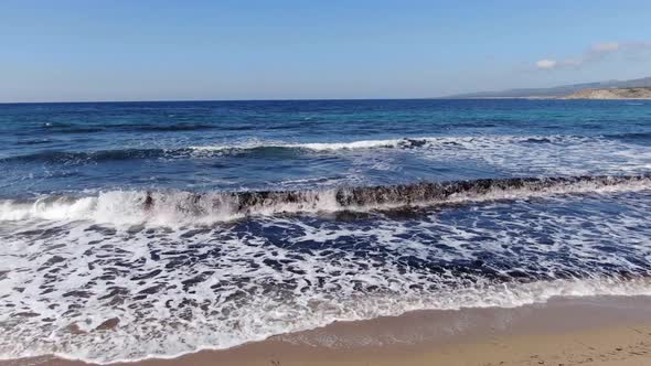 Camera Moves Along Sandy Summer Beach with Foamy Dark Blue Waves Rolling In