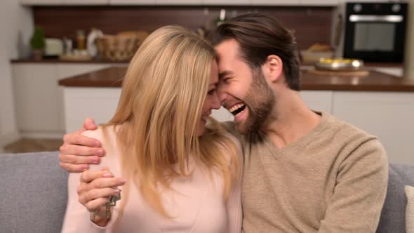 Young Married Couple Smiling Cheerfully and Showing Keys From a New Apartment