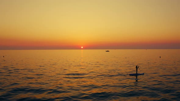 Girl with sup at sunset