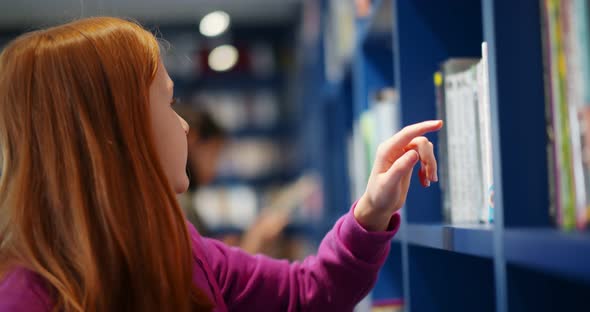 Redhead Preteen Schoolgirl Selecting Book in School Library