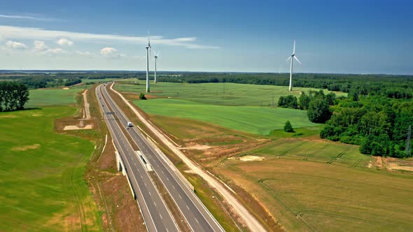Aerial view of golden field and wind turbines near highway. alt