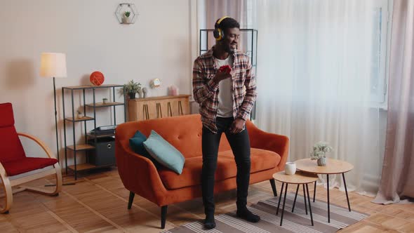 African American Young Man in Headphones Listening Music Dancing Singing in Living Room at Home