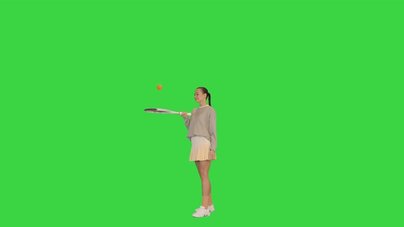 Young Woman Bouncing a Ball on Her Tennis Racket on a Green Screen Chroma Key