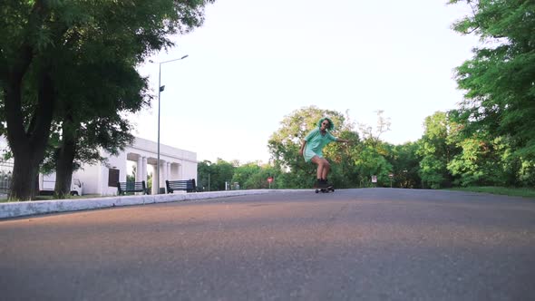 Beautiful Young Girl with Green Hair Riding on Longboard During Sunset Slow Motion
