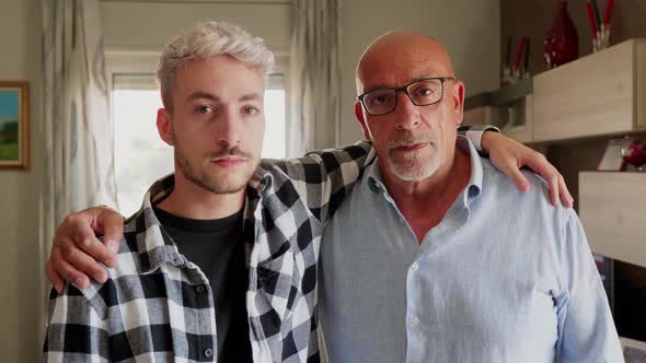 Father and son standing at home with arms around