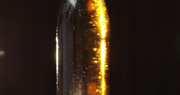 Bottle of Cold Beer on a Black Background. It Slowly Rotates. Condensate