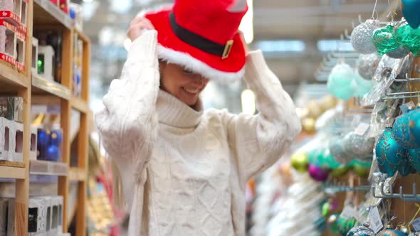 Christmas Shopping European Woman Dressed White Sweater Choose Santa Hat on Supermarket Put on Head