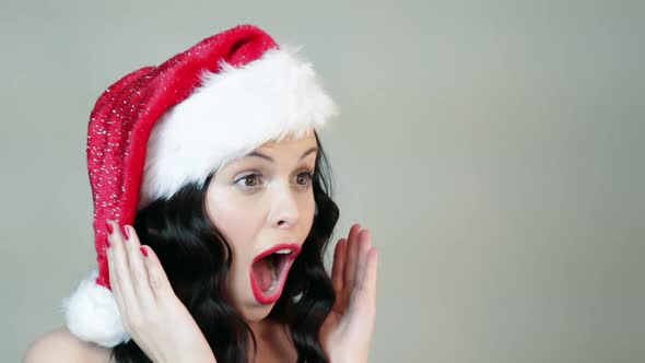 Young woman in santa hat being surprised