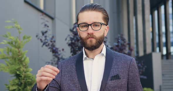 office manager in glasses and in stylish suit which poses on camera near modern office