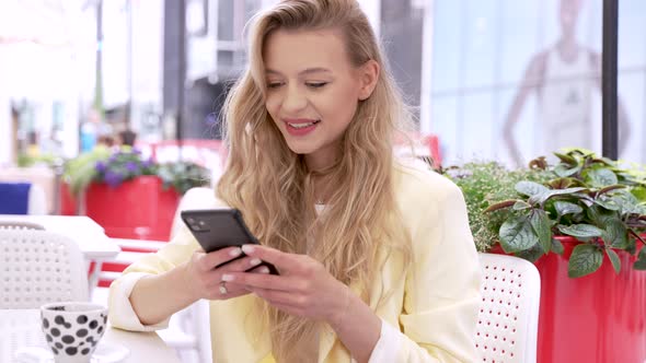 Smiling Woman Using Smartphone in Cafe