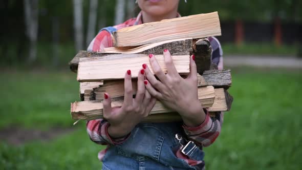 A young woman carries an armful of firewood in the village. Household woman