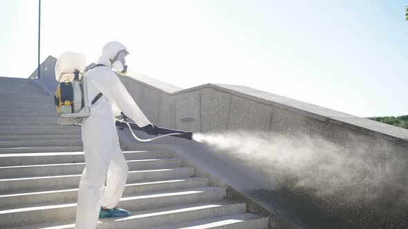 Disinfection of the City. Professional Worker in Protective Suit Cleans the Stairs.