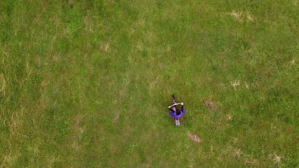 A Beautiful Little Girl Rides a Kids Bicycle Across the Field View From Above Aerial View