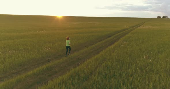 Sporty Child Runs Through a Green Wheat Field. Evening Sport Training Exercises at Rural Meadow. A