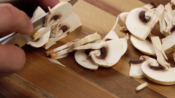 Men Hands Cutting Champignons with a Knife on Kitchen Table