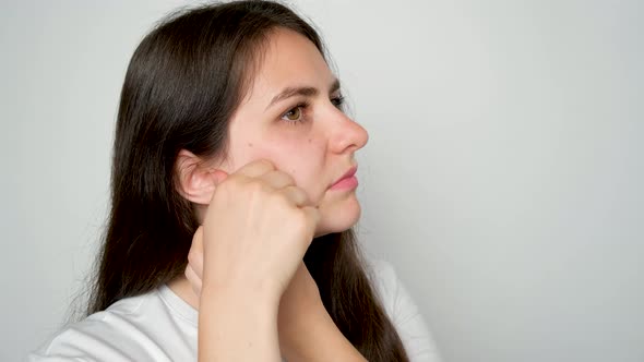 A Woman with Temporomandibular Joint Dysfunction Massages the Masticatory Muscles