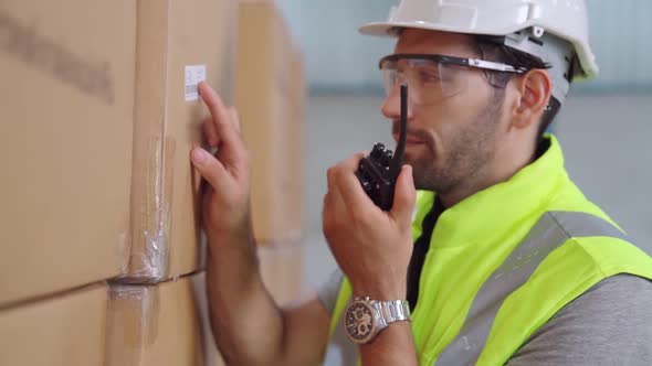 Professional Cargo Worker Talks on Portable Radio to Contact Another Worker