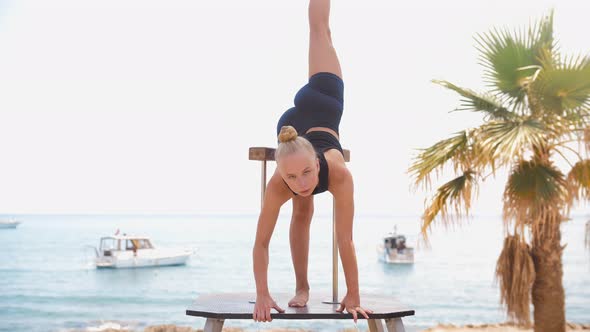 Young Female Gymnast Performs Gymnastic Exercises By the Sea