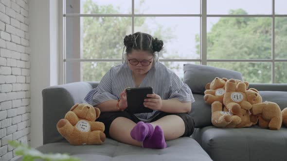 young Asian girl with Down's syndrome is playing a tablet alone in the room