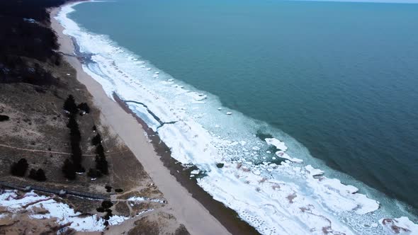 Parallax 4K drone video of a beach with frozen shoreline
