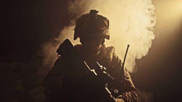 Silhouette of the Fully Equipped Soldier Moving Through Smokey Forest with Rifle Ready To Shoot