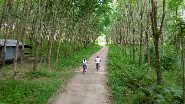 Couple Men and Women on Bicycle at a Rubber Plantation in Thailand