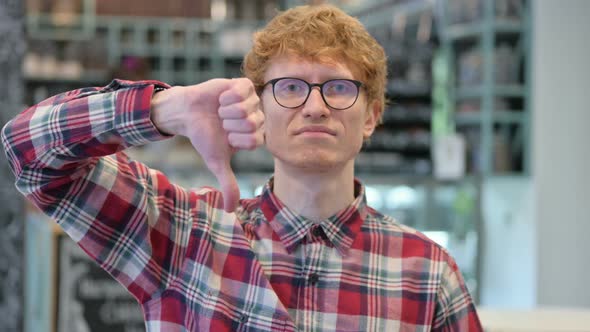 Young Redhead Man with Thumbs Down Gesture 