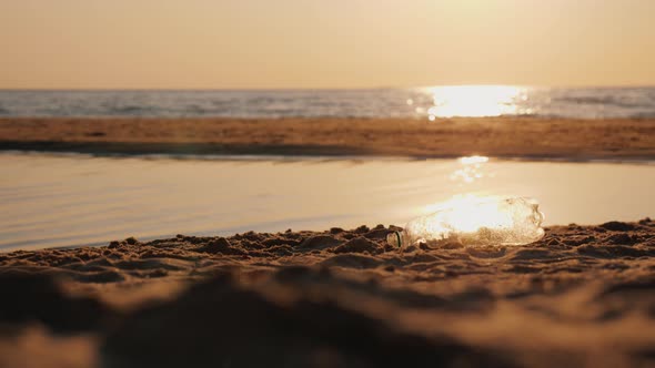 A Conscious Man Raises an Empty Plastic Bottle on the Beach. Caring for the Environment