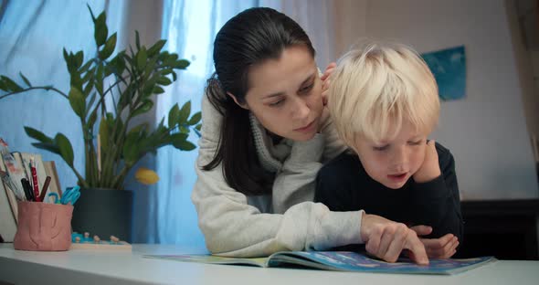 Young Mother with Preschool Child Boy Reading the Book with Labyrinths